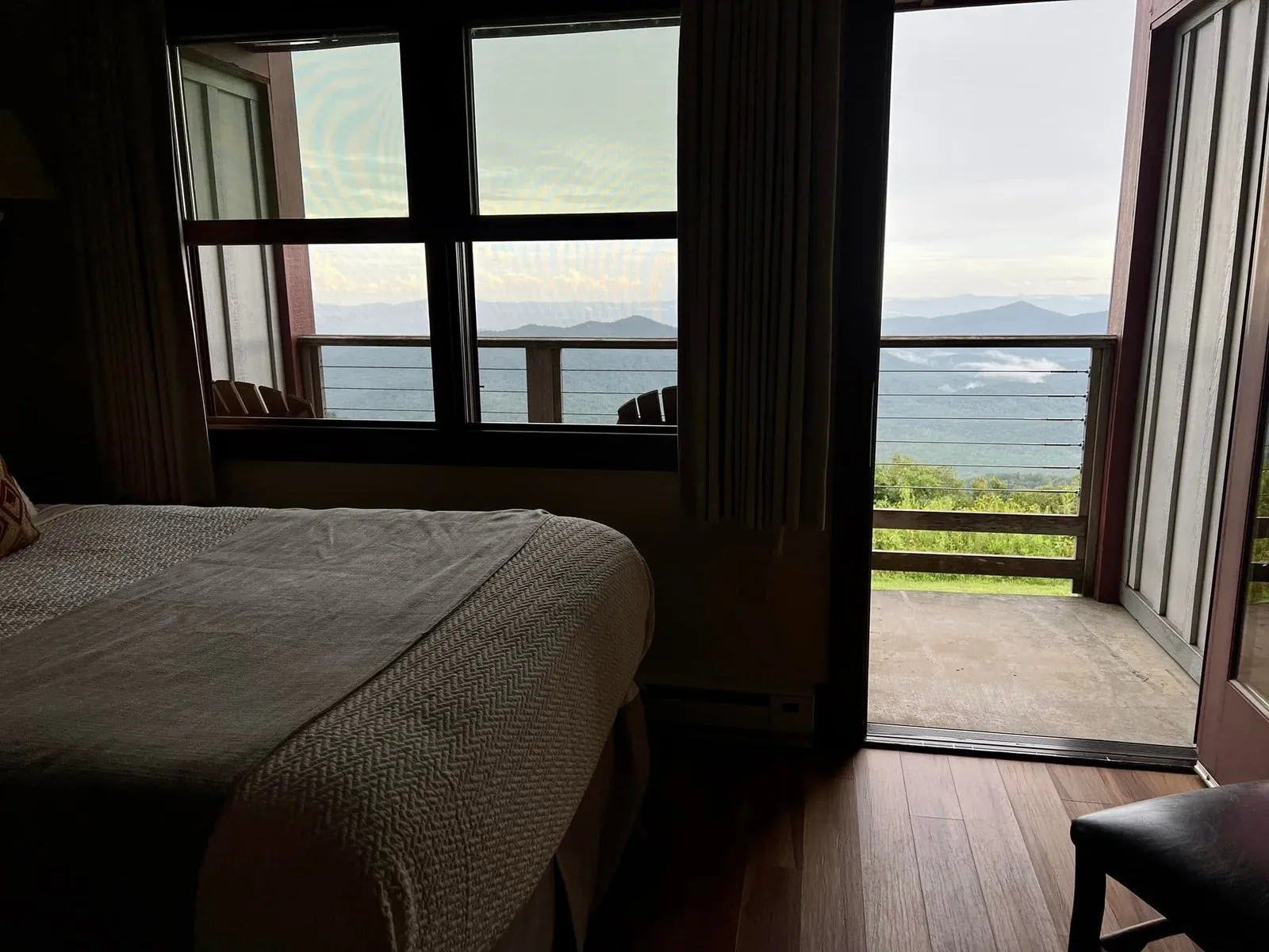 Pisgah Inn bedroom with a panoramic Blue Ridge mountain view through the windows and sliding glass door