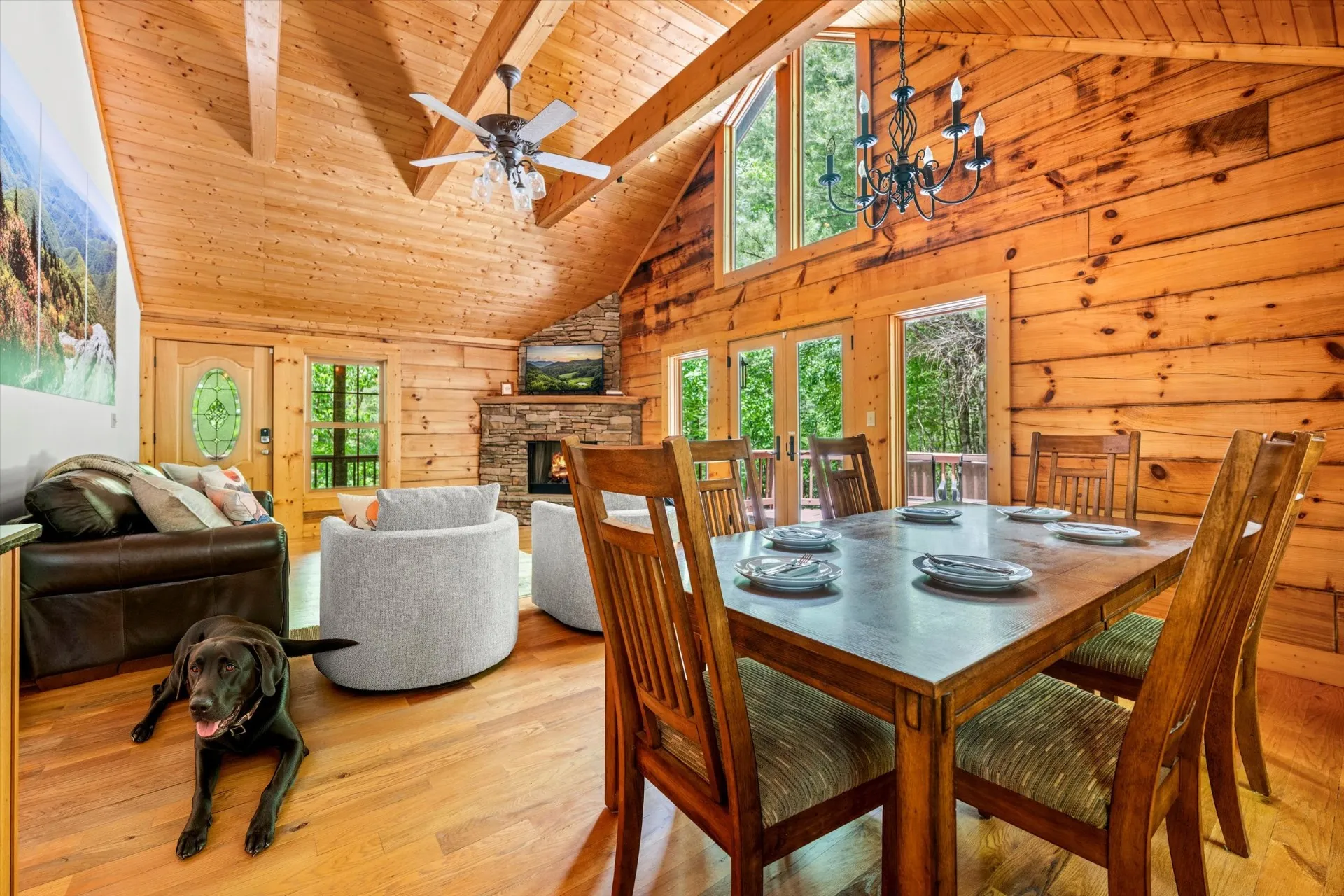 Dining area with a six-seat table, wrought-iron chandelier, and french doors opening onto the deck