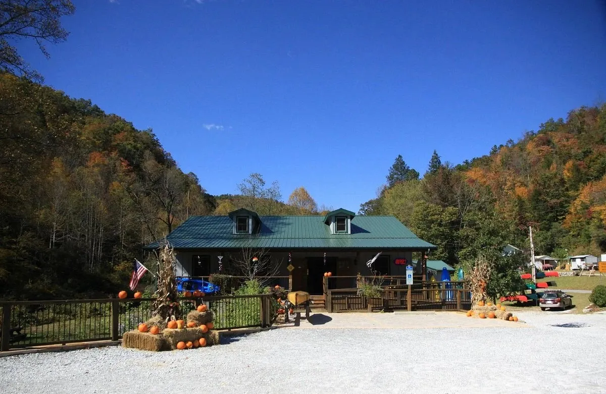 The Headwaters Outfitters shop at the Forks of the French Broad in Rosman, NC, with corn stalks, pumpkins, and hay bales out front under autumn ridges