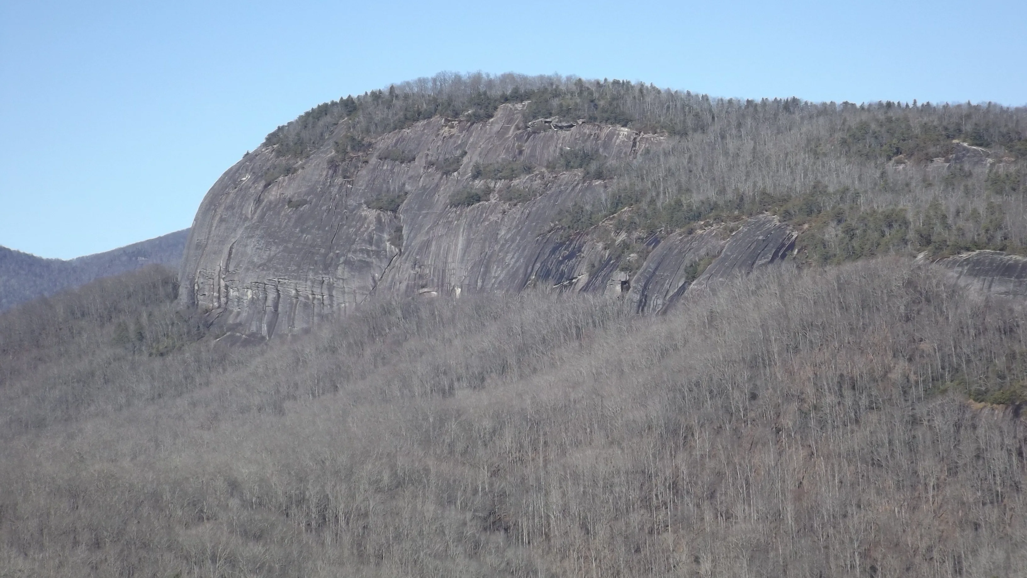 Looking Glass Rock in December, a bare granite dome rising above leafless gray forest under a clear blue sky