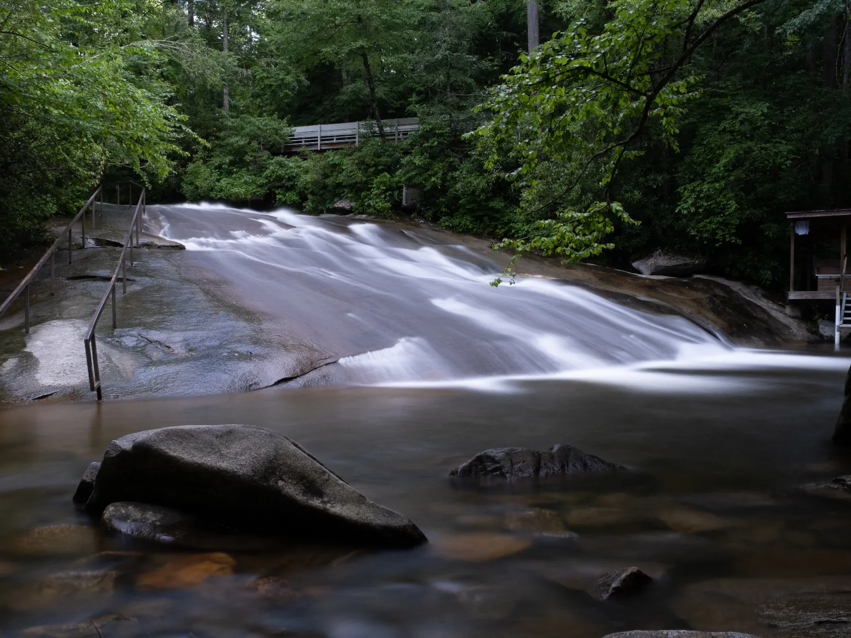 Long-exposure view of Sliding Rock with water rushing down the smooth granite slope in Pisgah National Forest