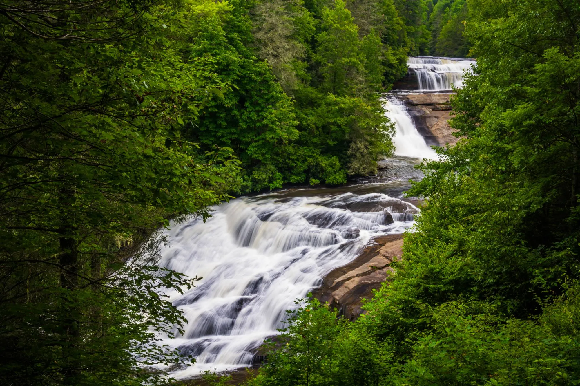 The three stacked cascades of Triple Falls in DuPont State Forest, framed by green forest
