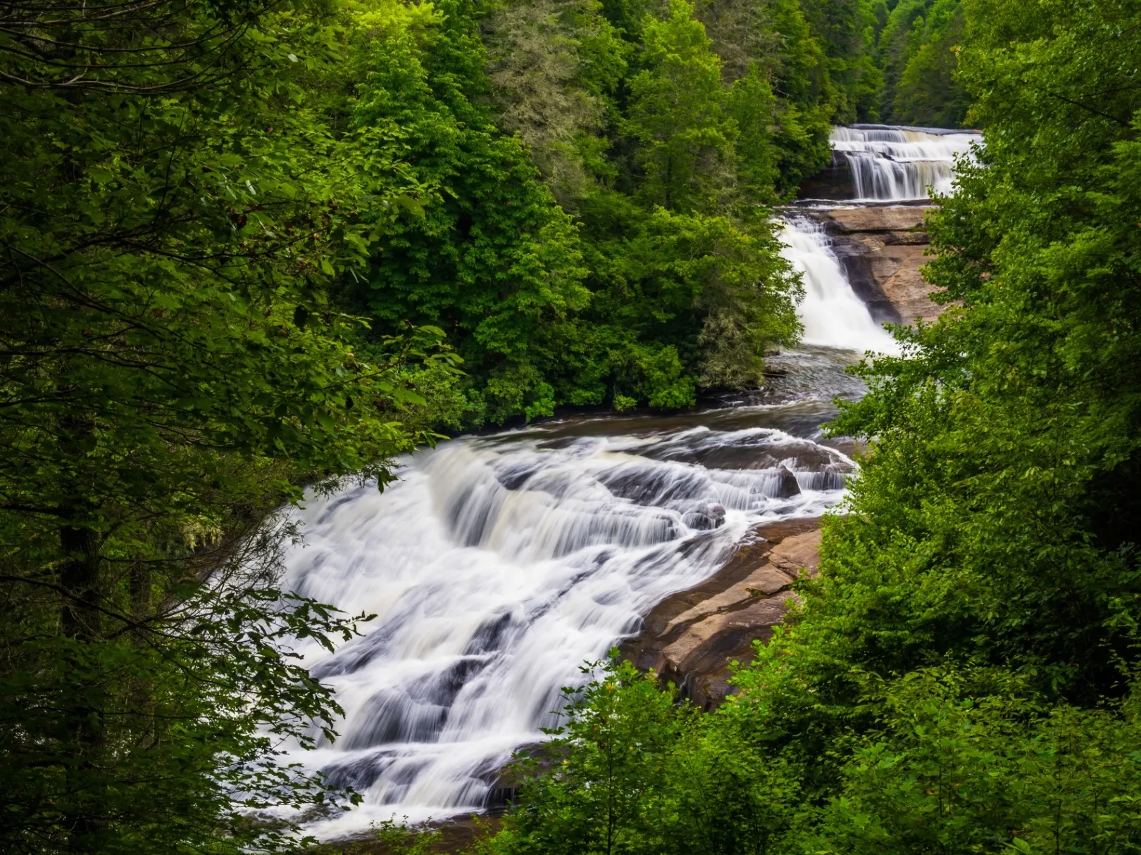 Triple Falls cascading through lush green forest in DuPont State Forest